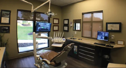 A dentist's office with a monitor and a chair. 