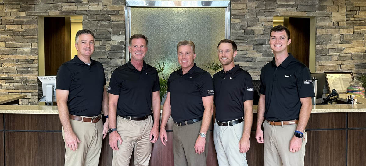 Five men in black shirts standing in front of a reception desk