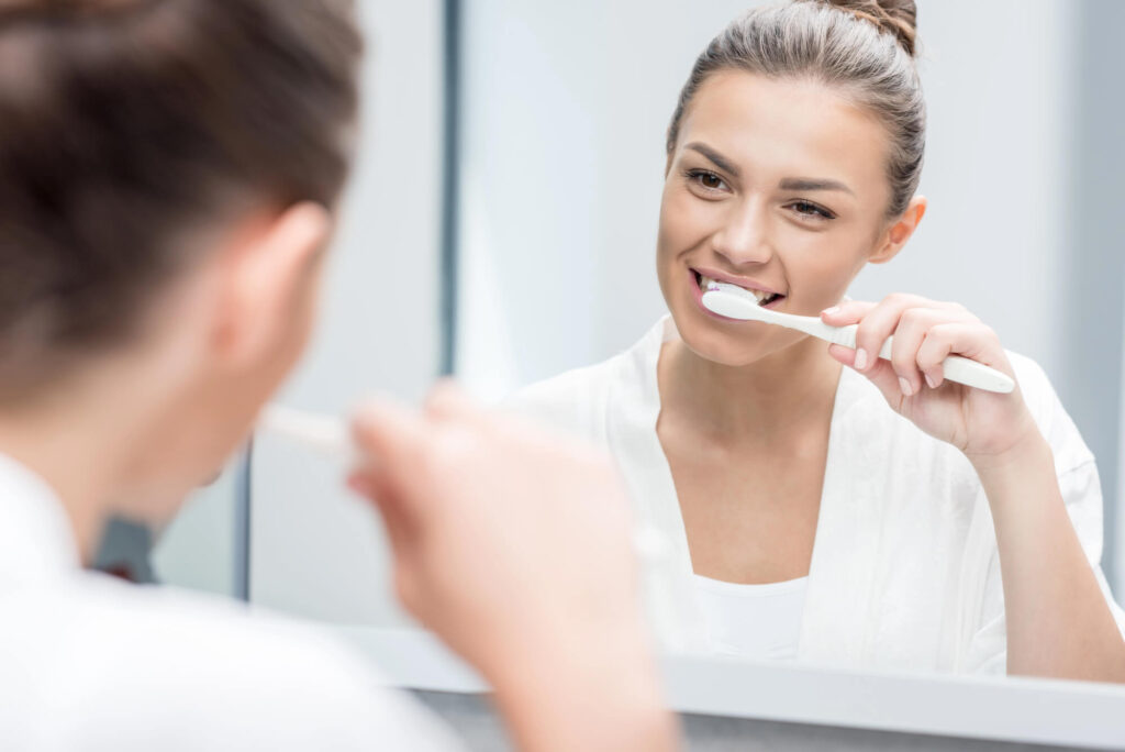 woman-brushing-her-teeth-as-told-by-her-dentist-Greenville-SC